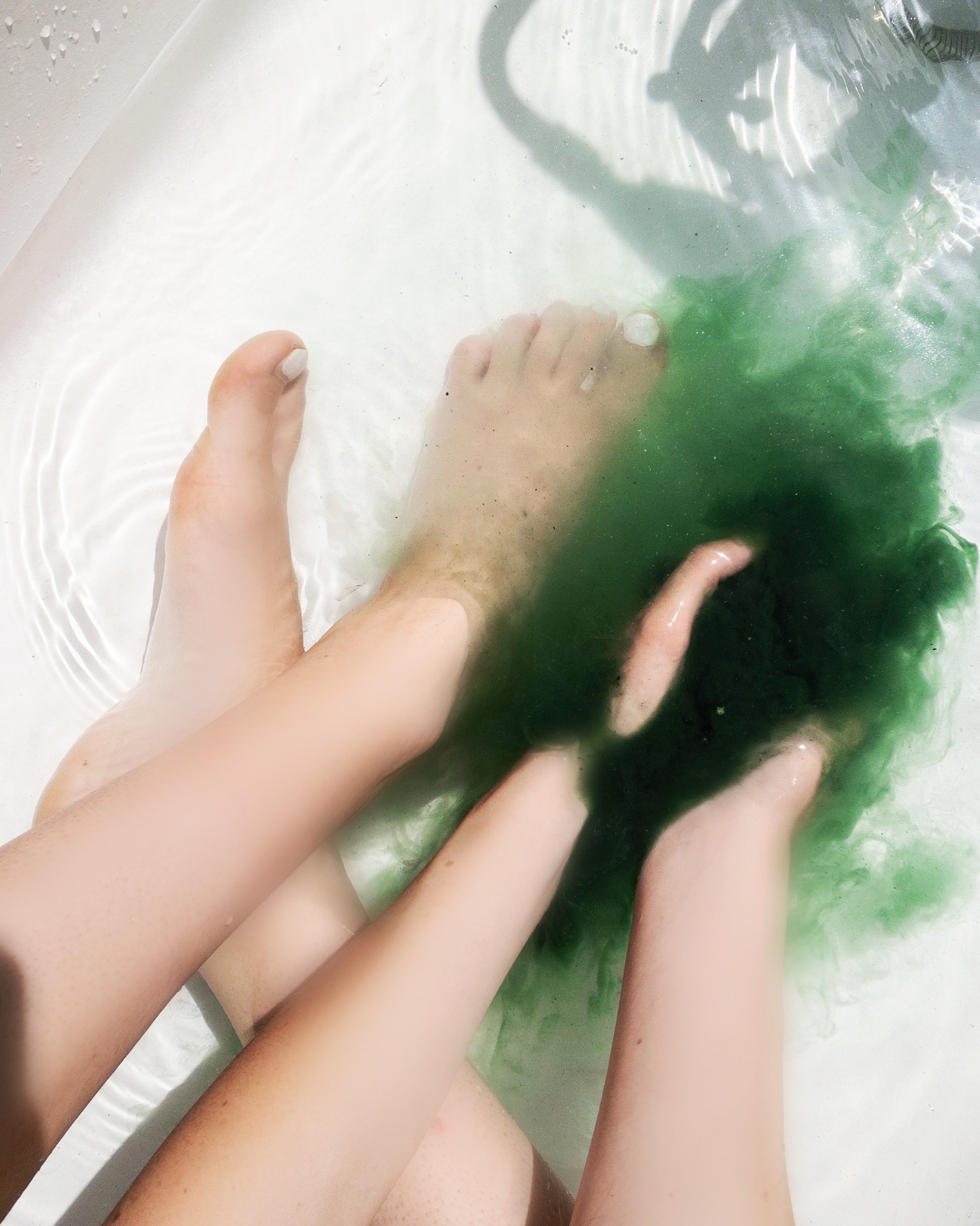 A person dissolving Heathen's green herbal bath soak into bath water. 
